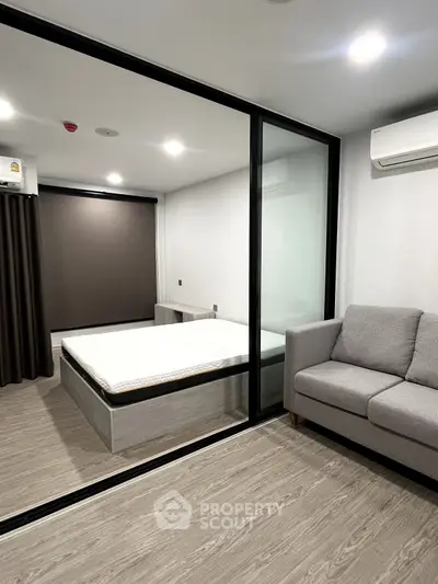 Modern bedroom with glass partition and cozy sofa in stylish apartment