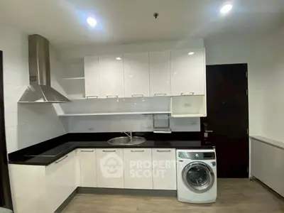 Modern kitchen with sleek white cabinets and built-in washing machine