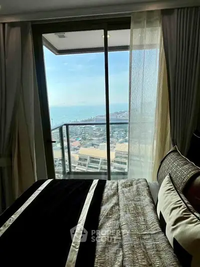 Luxurious bedroom with stunning ocean view from a high-rise balcony, featuring elegant bedding and sheer curtains.