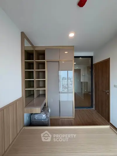 Modern bedroom with built-in storage and city view, featuring sleek wooden finishes and ample natural light.