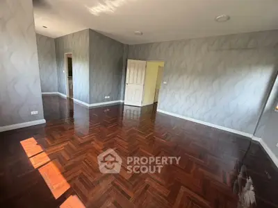 Spacious empty room with elegant wooden flooring and modern gray walls, perfect for customization.