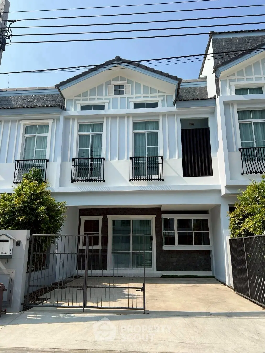 Charming townhouse with modern facade and gated driveway in sunny neighborhood.