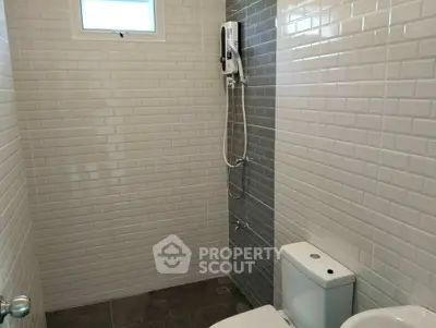 Modern bathroom with sleek white tiles and compact shower setup