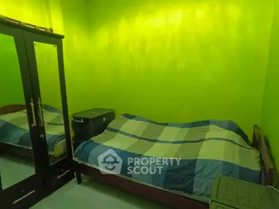 Cozy bedroom with vibrant green walls and mirrored wardrobe