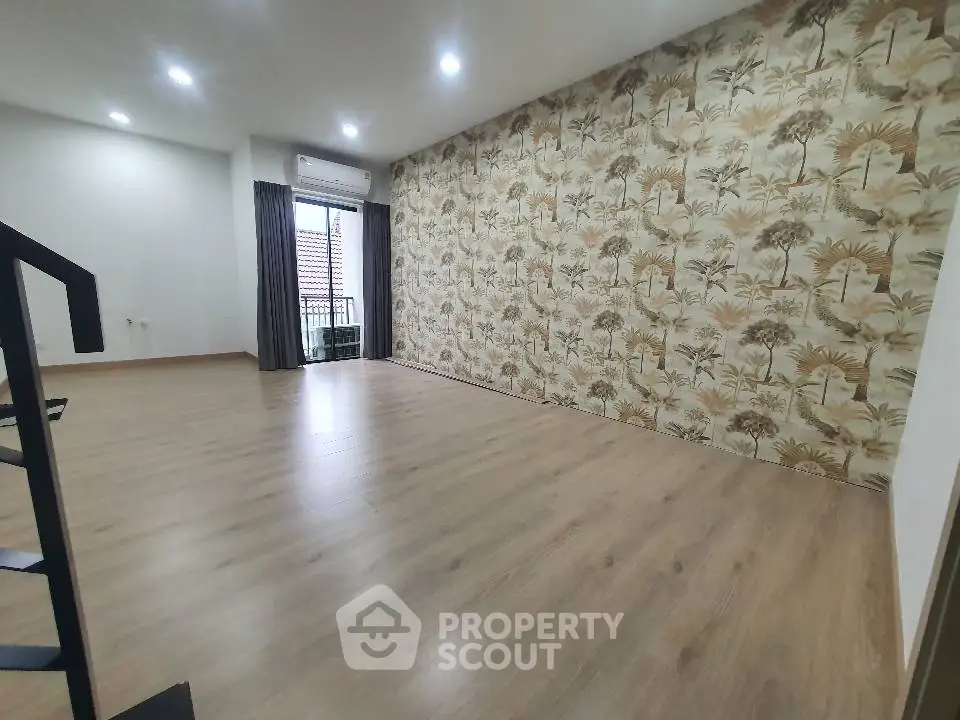 Spacious living room with elegant wallpaper and balcony access