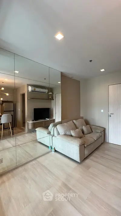 Spacious modern living room with mirrored wall and cozy sofa in a stylish apartment.