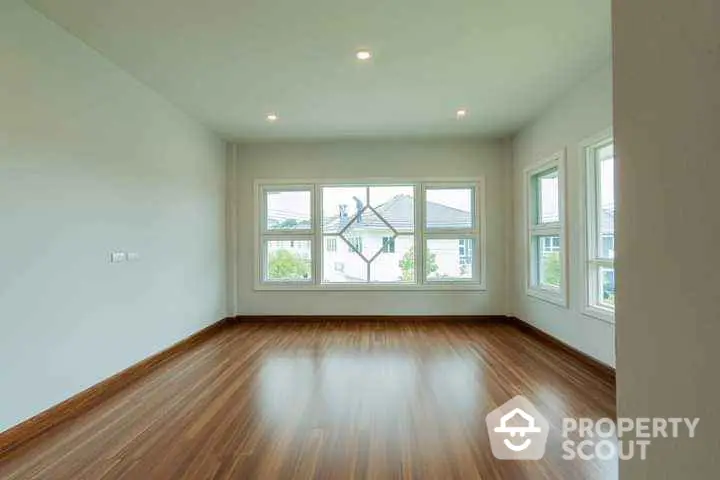 Spacious empty room with large windows and wooden flooring