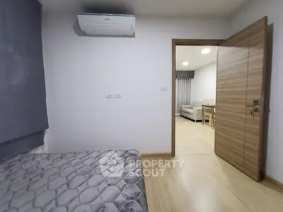 Modern bedroom with air conditioning and open door to living area in stylish apartment.