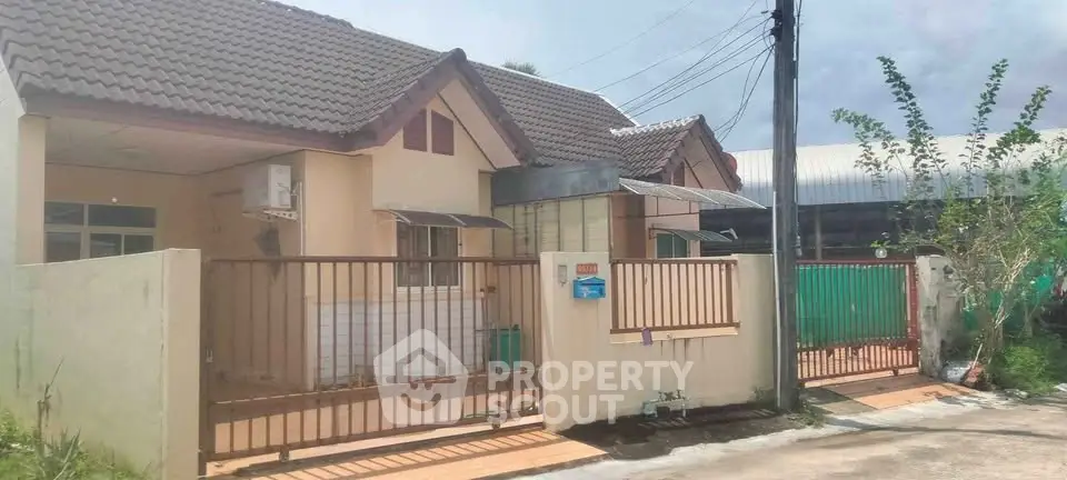 Charming single-story house with gated entrance and tiled roof in a serene neighborhood.