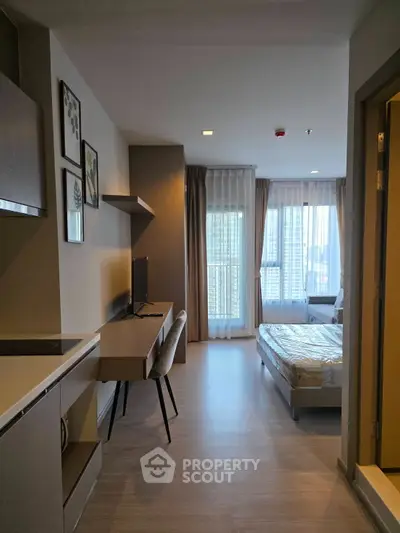 Modern studio apartment with open layout, featuring a cozy bed, sleek kitchen, and ample natural light.