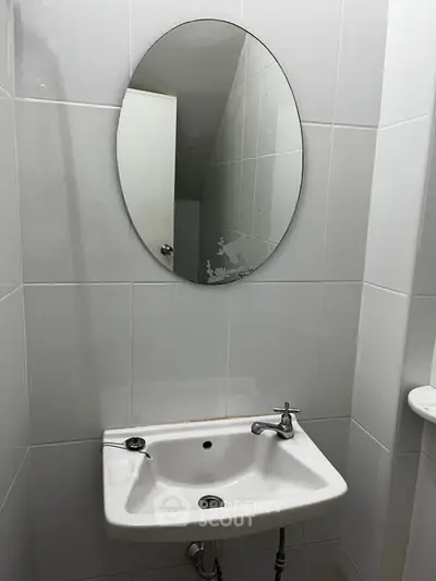 Compact bathroom with oval mirror and white sink, ideal for small spaces.