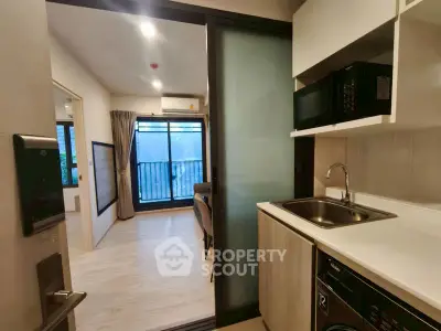 Modern compact apartment with kitchenette and balcony view, ideal for urban living.