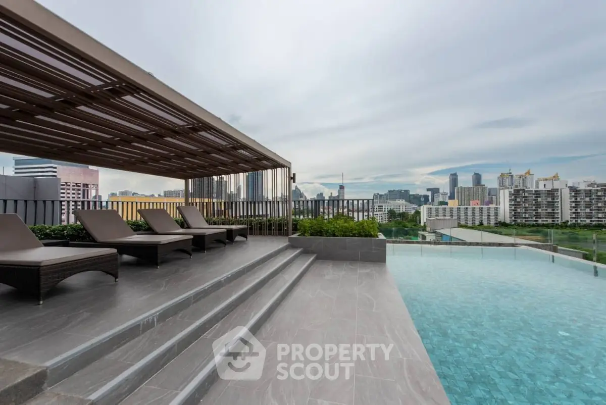 Luxurious rooftop pool with stunning city skyline view and modern lounge area.