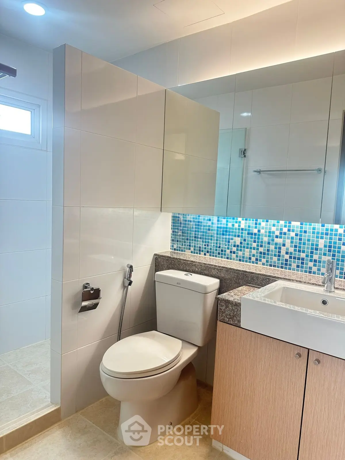Modern bathroom with sleek design, featuring a stylish sink, toilet, and mosaic tile accents.