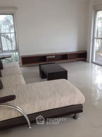 Spacious living room with modern sofa and large windows offering natural light.
