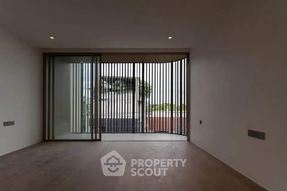 Spacious modern living room with floor-to-ceiling windows and sliding doors opening to a balcony.
