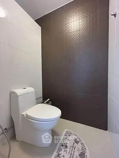 Modern bathroom with sleek design and neutral tiles, featuring a contemporary toilet.