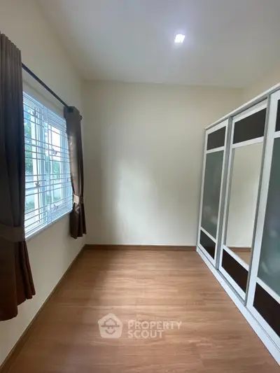 Spacious room with large window and mirrored wardrobe, perfect for customization.