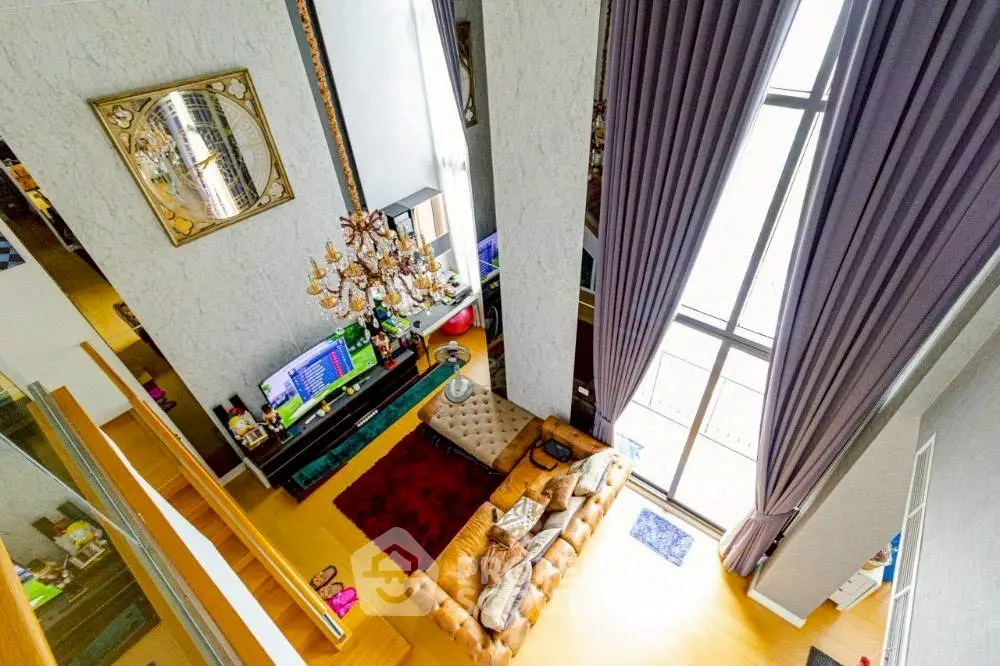 Luxurious high-ceiling living room with elegant chandelier and floor-to-ceiling windows.
