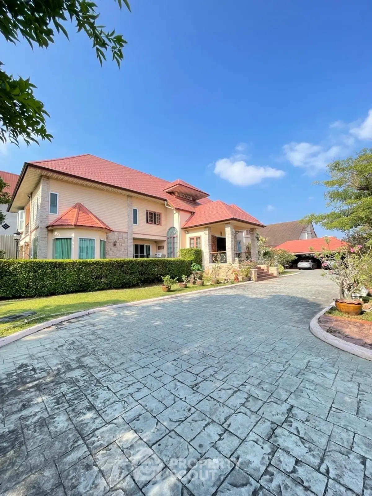 Stunning two-story house with red roof and spacious driveway under clear blue sky.