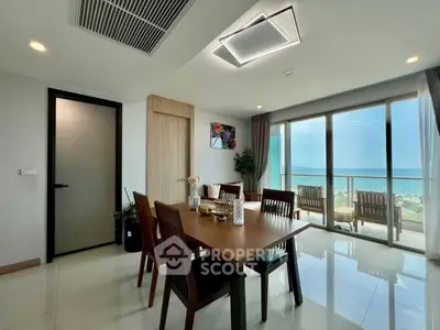 Modern dining area with ocean view, elegant furniture, and large windows in a luxury apartment.