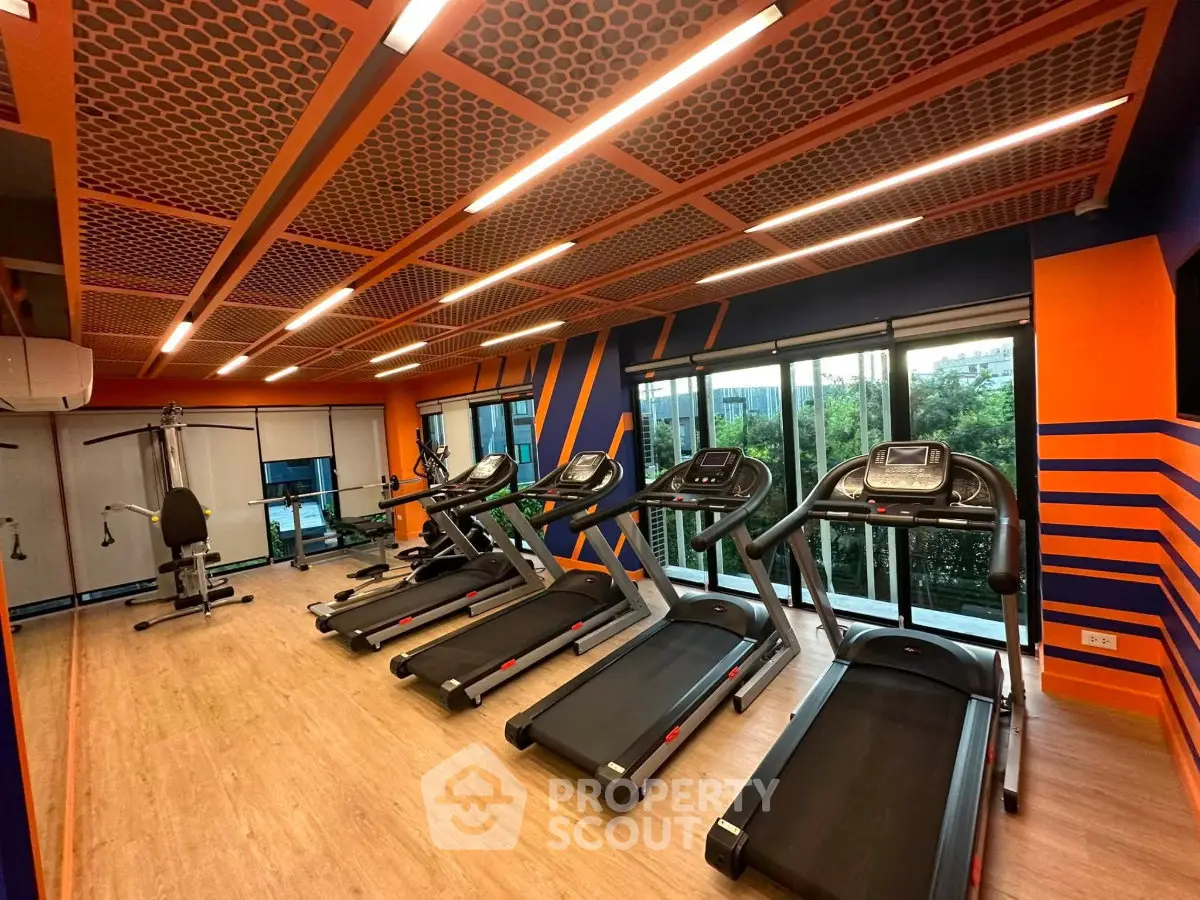 Modern gym with treadmills and exercise equipment in vibrant orange and blue decor