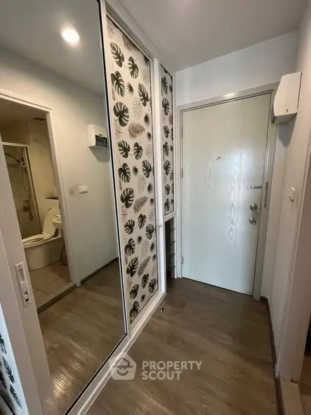 Modern apartment entrance with stylish mirrored closet and wooden flooring
