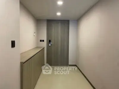 Modern minimalist hallway with sleek wooden door and recessed lighting