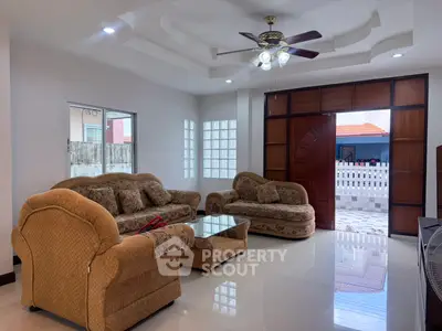 Spacious living room with elegant furniture and ceiling fan, featuring large windows for natural light.