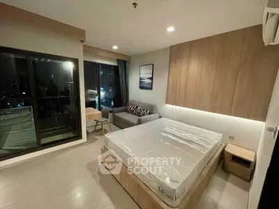 Modern bedroom with large window and city view, featuring a cozy bed and stylish decor.