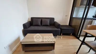 Cozy living room with modern sofa and wooden coffee table, adjacent to a sleek kitchen area.