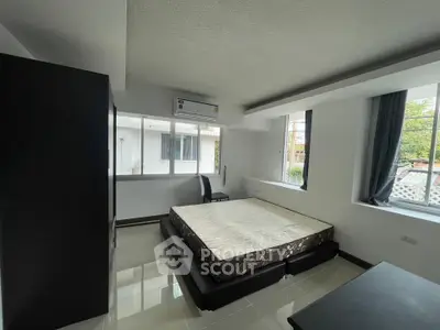 Spacious bedroom with large windows and modern furnishings in a stylish apartment.