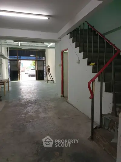 Spacious industrial-style interior with open layout and staircase, ideal for creative workspace or studio.