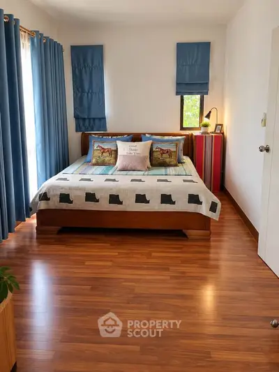 Cozy bedroom with wooden flooring and stylish blue curtains