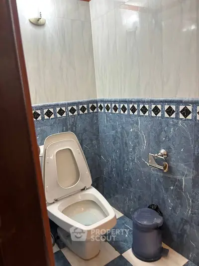 Modern bathroom with blue and white tile design and sleek fixtures.