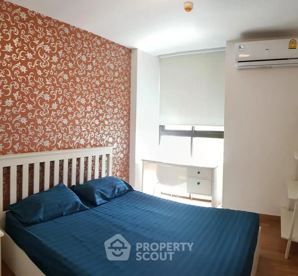 Cozy bedroom with stylish wallpaper and modern furnishings in a bright apartment.