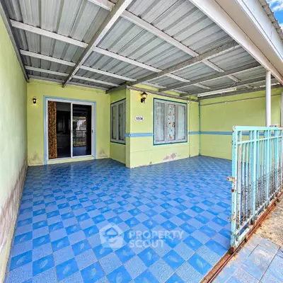 Spacious covered patio with blue tiled flooring and sliding glass doors, perfect for outdoor relaxation.