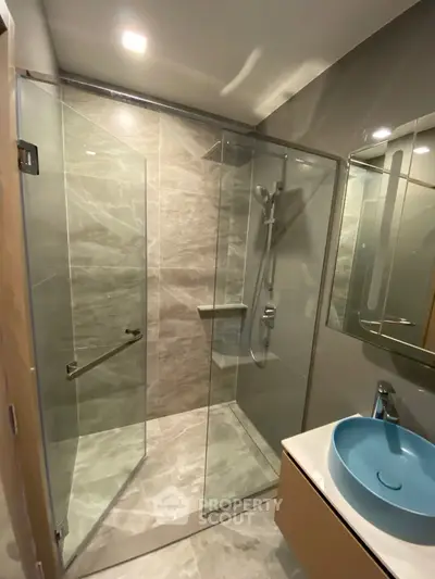 Modern bathroom with glass shower enclosure and stylish blue basin