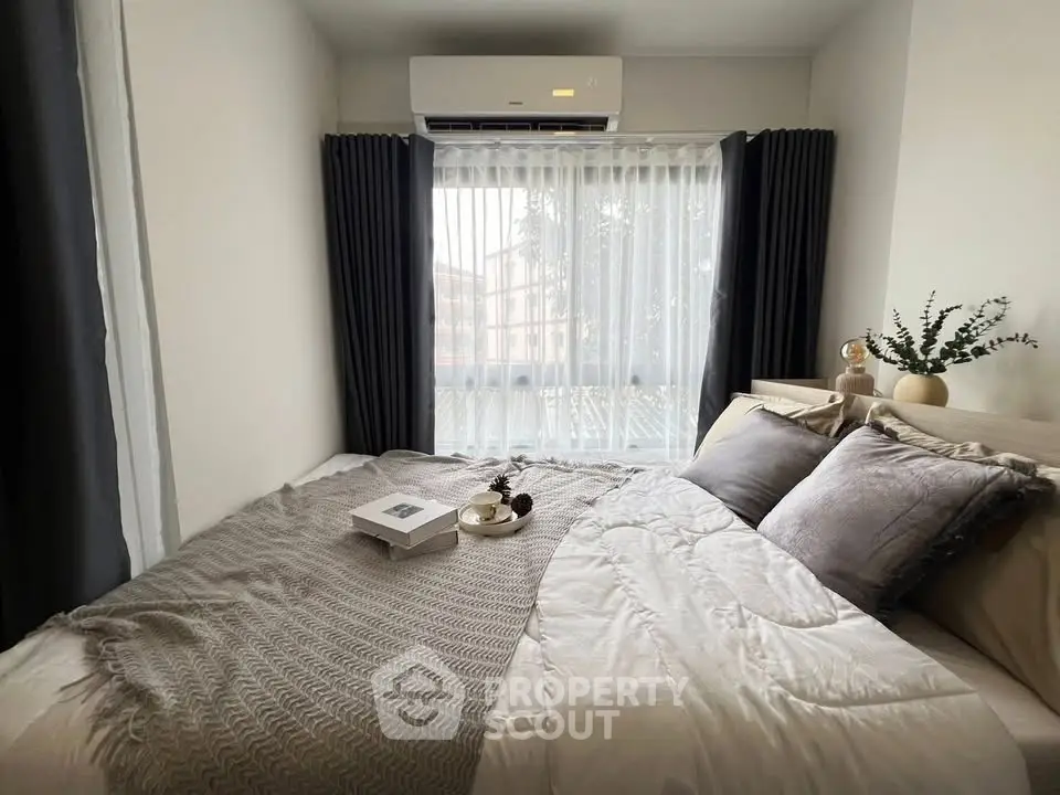 Cozy bedroom with modern decor and large window, featuring elegant bedding and air conditioning.