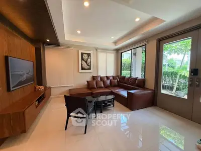 Modern living room with sleek furniture and large windows offering garden views.