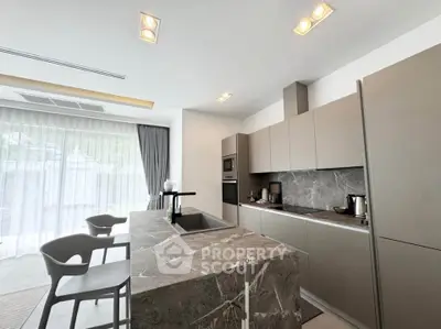 Modern kitchen with sleek design and marble countertops, featuring built-in appliances and stylish seating.