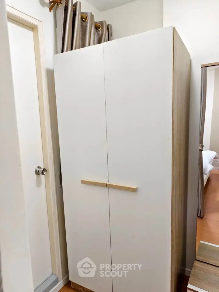 Compact storage wardrobe in a cozy bedroom corner with wooden flooring.
