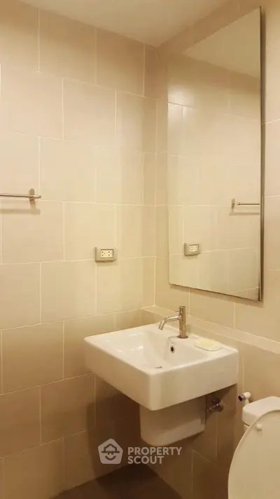 Modern bathroom with sleek sink and large mirror in a minimalist design.