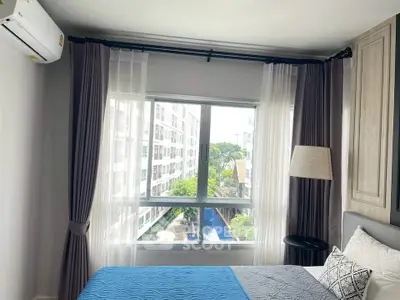 Bright bedroom with large window offering a stunning view of the cityscape, featuring modern decor and cozy ambiance.