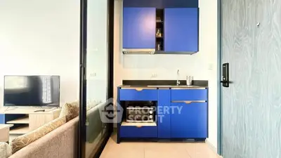 Modern compact kitchen with blue cabinets and integrated appliances in stylish apartment.