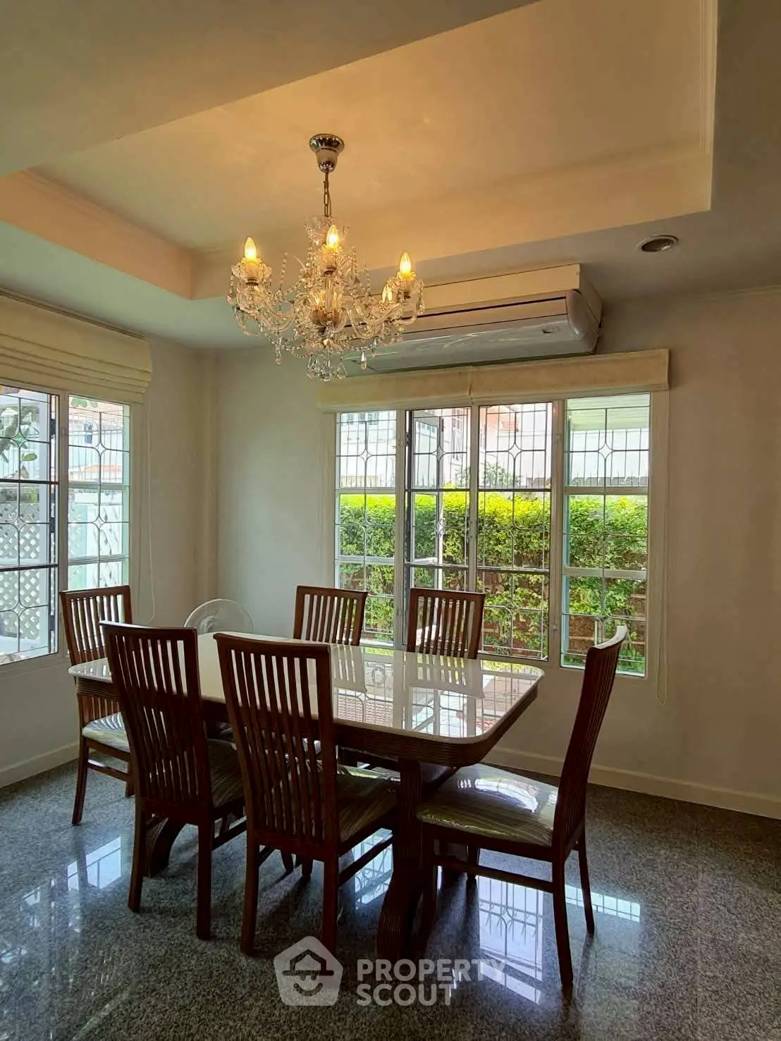Elegant dining room with chandelier and large windows overlooking garden.