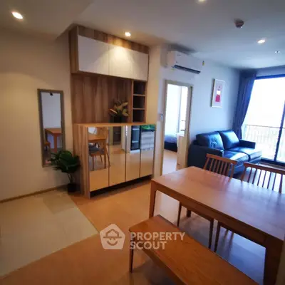 Modern open-plan living and dining area with stylish wooden furniture and large windows.
