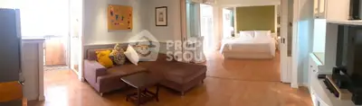 Spacious open-plan living room with cozy seating and elegant bedroom view, perfect for modern living.