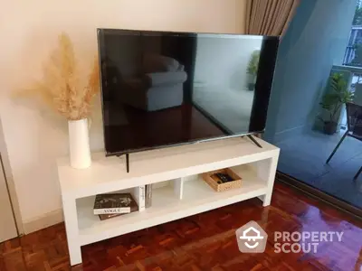 Elegant living space with polished hardwood floors featuring a sleek flat-screen TV and a chic white entertainment console.