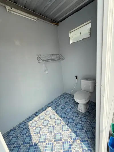 Compact bathroom with blue tiled floor and white walls, featuring a toilet and wall-mounted shelf.